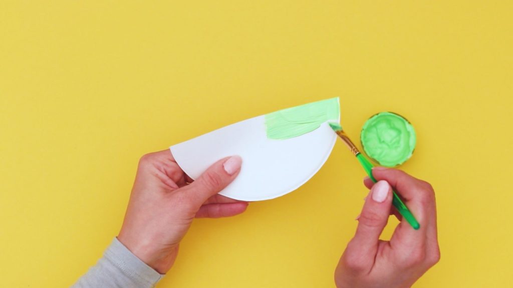 Image showing a semi-circle cut out from a paper plate being painted green.