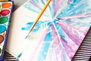 Watercolour and Oil Pastel Resist Snowflake Kids Art - This watercolour and oil pastel resist Snowflake art idea for kids is perfect for the Winter season. Children will love discovering the secret snowflake, while playing with and mixing the watercolour paints to create a pretty Winter scene.