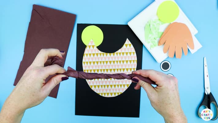 Adding a tissue paper branch to the Handprint Owl Craft.