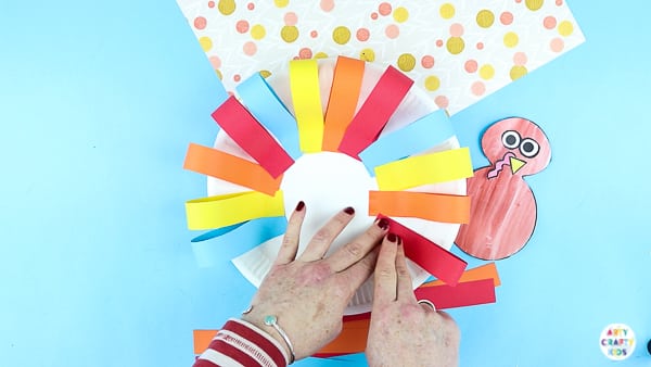 Arty Crafty Kids | Creating a paper plate turkey craft with strips of paper.