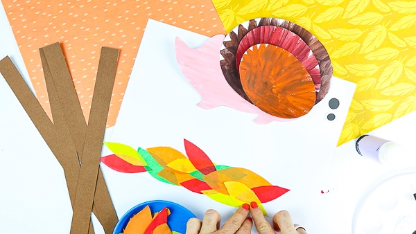 Cut out a handful of leaf shapes from tissue paper, using colorful Autumn color shades.