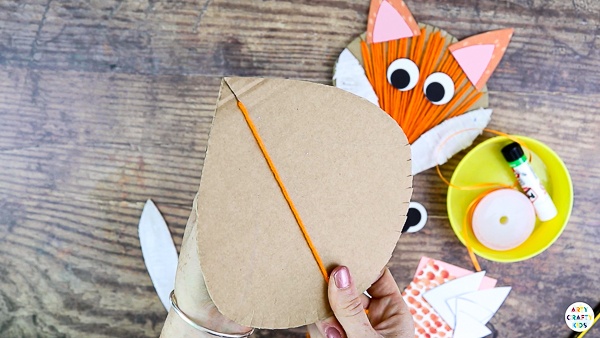 Start from the large slit and begin wrapping the cardboard with yarn.