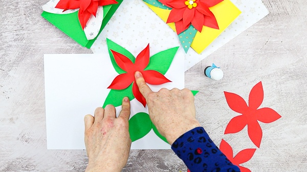 Once the poinsettia petals have been pinched, glue for the first and largest layer on top of the leaves.