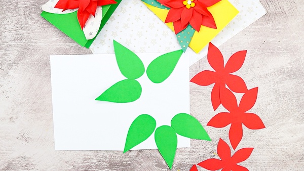 Secure the green leaves to the a piece of white cardstock to start building the Christmas card.