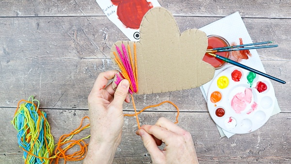 Begin wrapping the yarn around the cardboard, using the cardboard to secure the yarn.