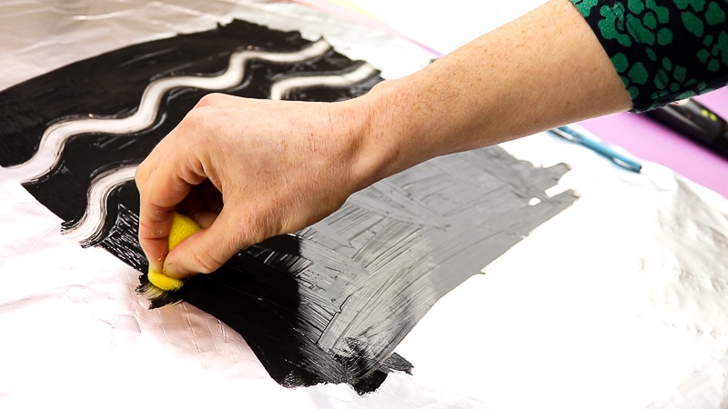 Image showing a pattern being drawn into black paint on aluminium foil with a sponge - the first print of the mono print process.