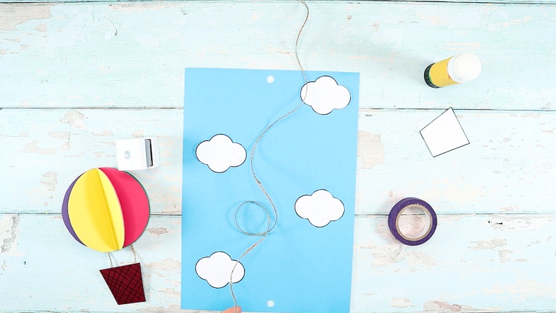 Image showing cloud stuck to blue card stock with holes added either end to the card. A long piece of string falls in the middle.