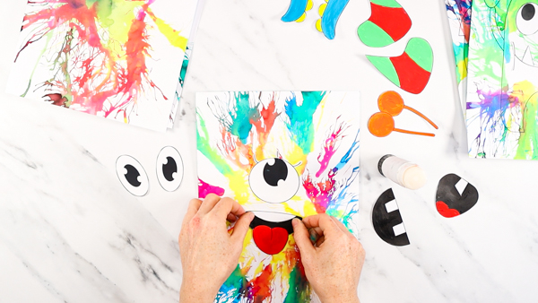 Image showing a printable monster eye and mouth being glued to painting with straw art.