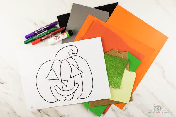 Image showing bright orange, green and black card, our printable Pumpkin template, a glue stick and glitter glue.