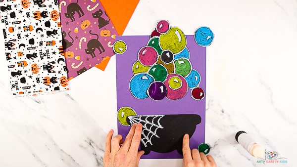Image showing the cauldron and bubbles cut from the black card stock and glued onto a purple piece of card stock.