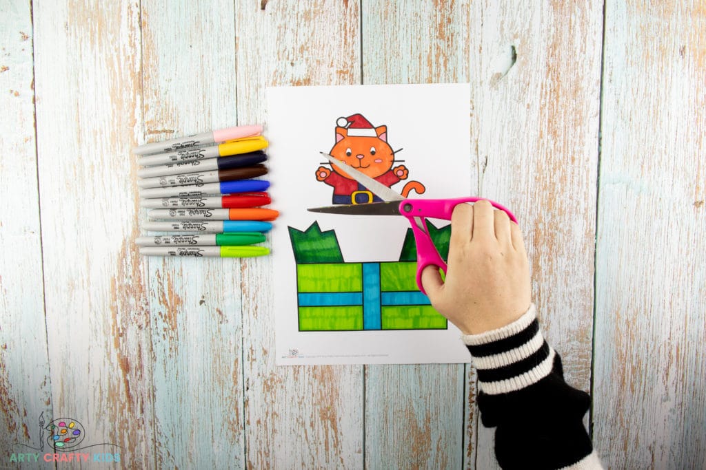 Image showing the Santa Claws printable colored and a pair of hands holding scissors.
