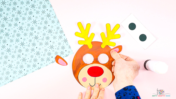 Image showing hands adding antlers and ears to the reindeer's head.