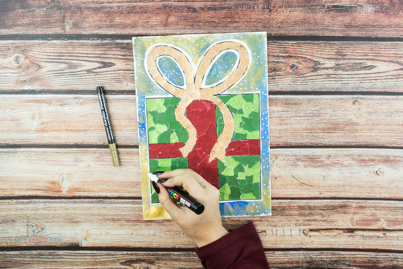 Image showing a hand drawing white snow drops onto the background of the Christmas Present art.