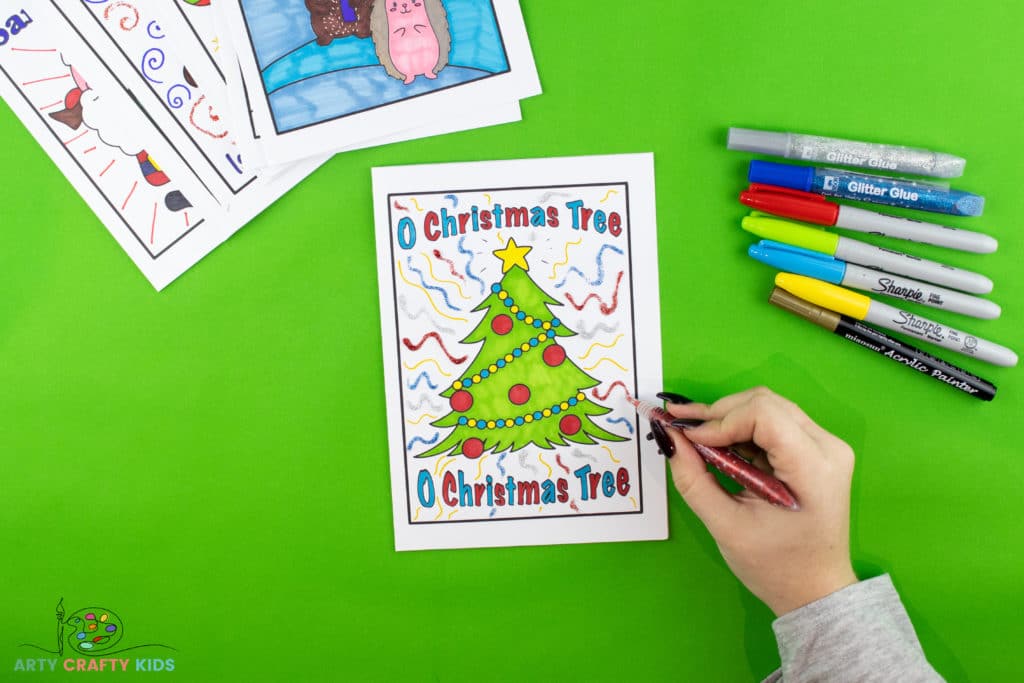 Image showing some glitter glue being applied to the christmas card, to add some fun details in the background.