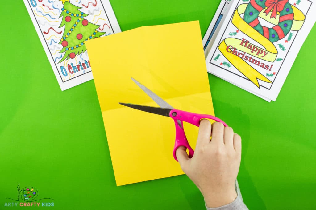 Image showing scissors ready to cut the colored card stock, using the folded lines as a guide.