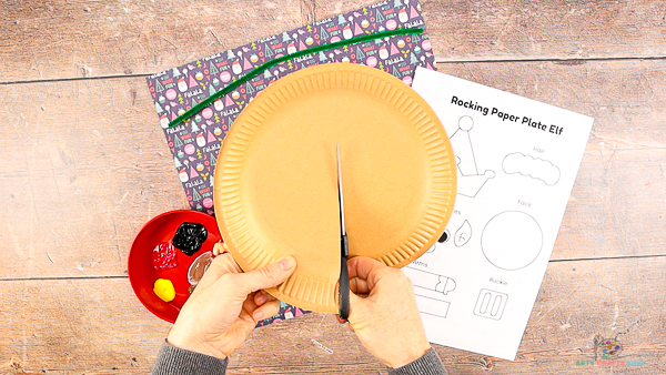 Image showing hands cutting into a paper plate, approximately half way.