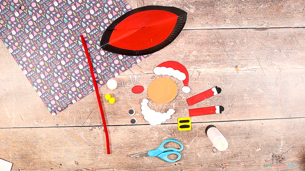 Image showing a painting paper plate and cut out Santa elements from the printable template.