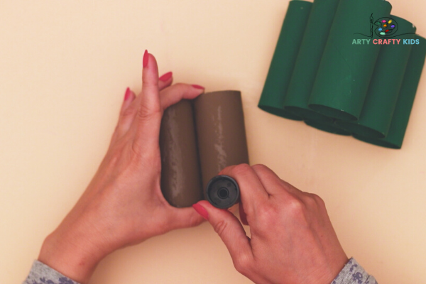 Image showing hands applying glue to the Christmas tree stumps - two brown paper roll.