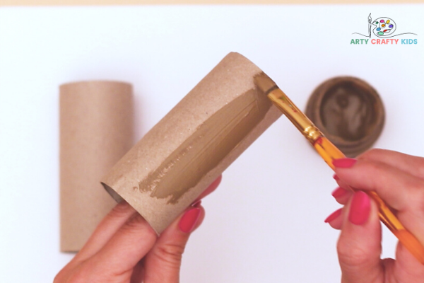 Image showing hands painting two paper rolls brown.