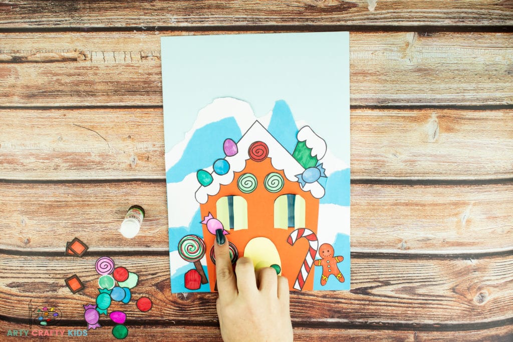 Image showing candy pieces being glued on to the gingerbread house.