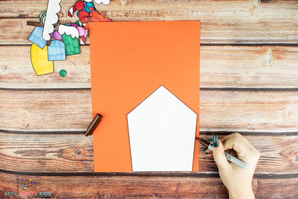 Image showing the House element of the template being drawn around on to orange card stock.