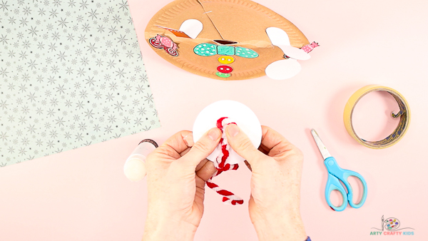 Image showing hands securing a pipe cleaner to the back of a gingerbread man's head.