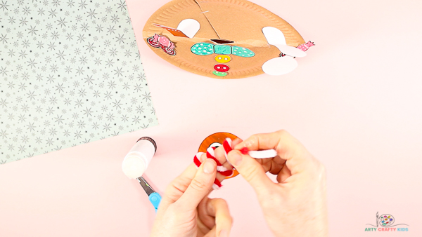 Image showing hands folding the pipe cleaner around a pair of fingers to form a coil.