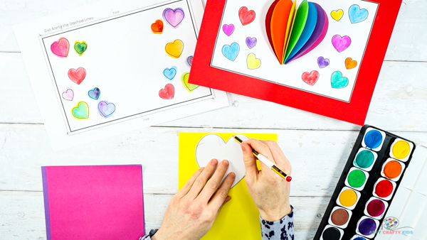 Image showing a hand tracing one of the heart cut outs onto yellow card stock.