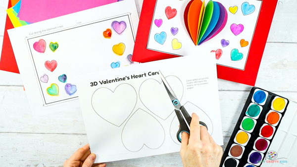 Image showing hands with a pair of scissors preparing to cut out a single heart from the template.