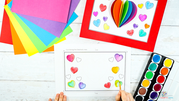 Image showing hands coloring in the hearts on the printable heart template. 
