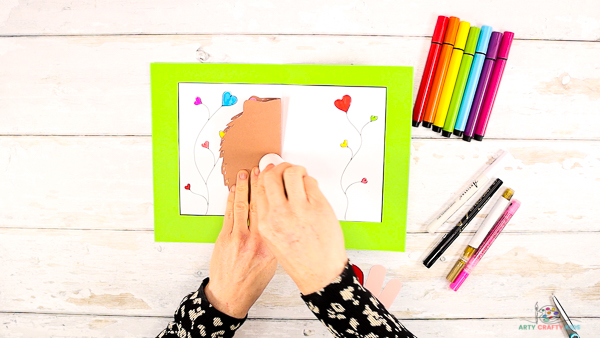 Image showing hands glueing the hedgehog to the inside of the card. 