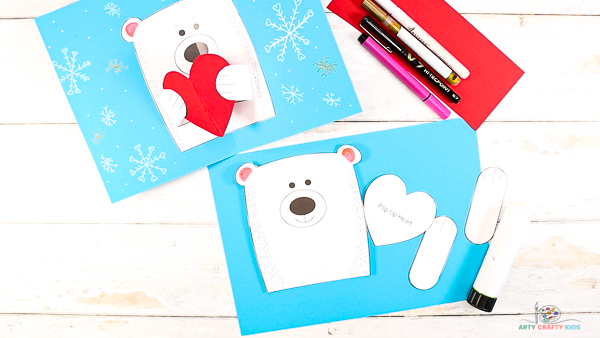 Image showing cut out polar bear elements against a sheet of blue card stock.