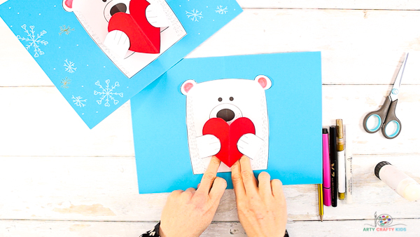 Image showing hands affixing the heart to the polar bears tummy.