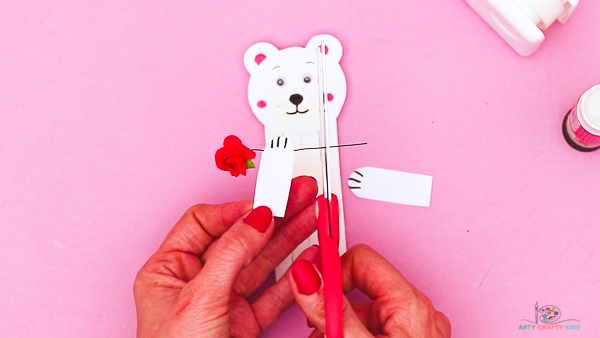 Image showing hands securing a small artificial rose to the polar bears arm.