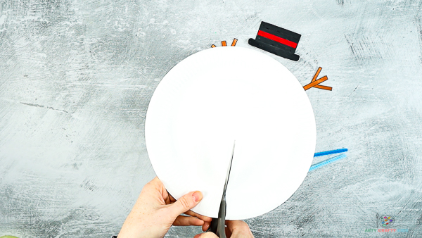 Image showing hands with a pair of scissors cutting to the center of the paper plate.