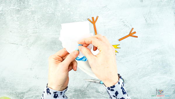 Image showing hands securing the assembled snowman's hat to the top of the pipe cleaner.