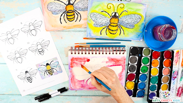 Image showing hands applying watercolor paint around the sketch of the bee.