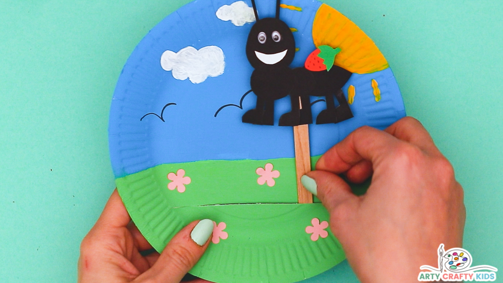 Image showing hands threading a puppet into the opening of the paper plate.