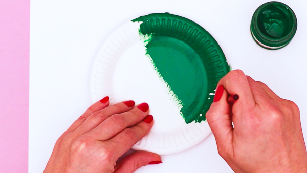 Image showing hands painting a paper plate green to create the leprechaun's body.