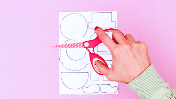 Image showing hands with a pair of scissors to suggest the cutting out of the printable leprechaun elements.