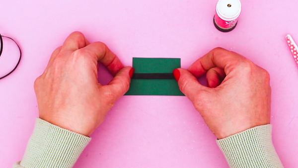 Image showing hands placing a strip of black ribbon across the a green leprechaun hat.