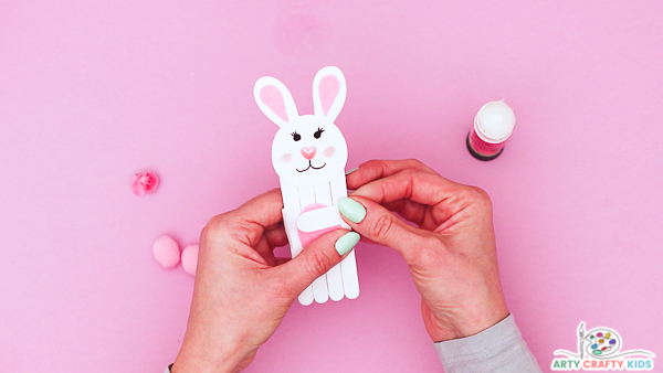 Image showing hands gluing the arms  onto the Popsicle sticks.