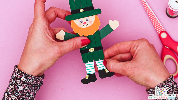 Image showing hands securing the arms and legs to the back to the leprechaun's popsicle body.