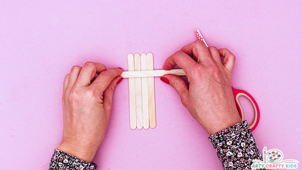 Image showing hands aligning the popsicle stick's to create the leprechaun. 

Image features a set of four sticks.