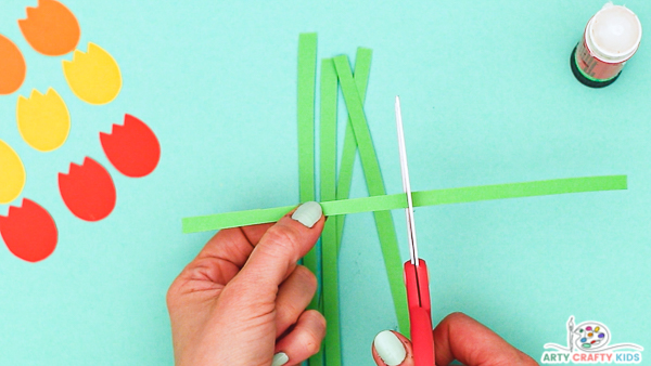 Image showing hands cutting several strips out of green paper.