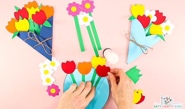 Image showing hands gluing a fourth tulip in a row to the inside of the bouquet.