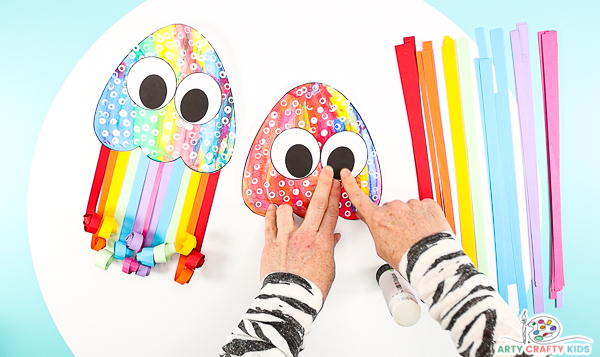 Image showing hands glueing the eyes onto the painted paper jellyfish.