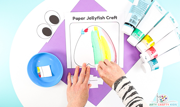 Image showing hands scraping the paint with a square cut out from the top of the jellyfish to the bottom.