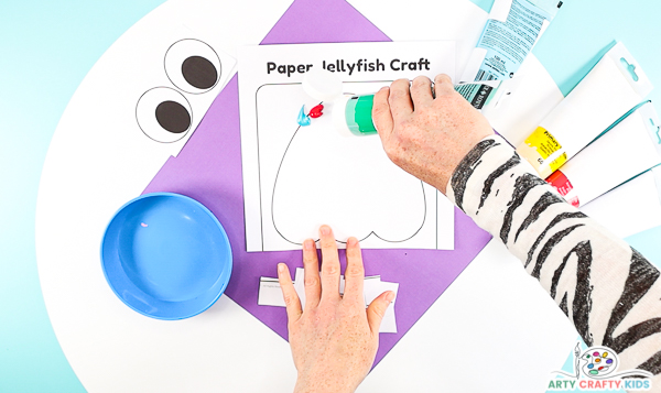 Image showing hands squirting blots of paint to the top of the jellyfish shape at the top of the template.