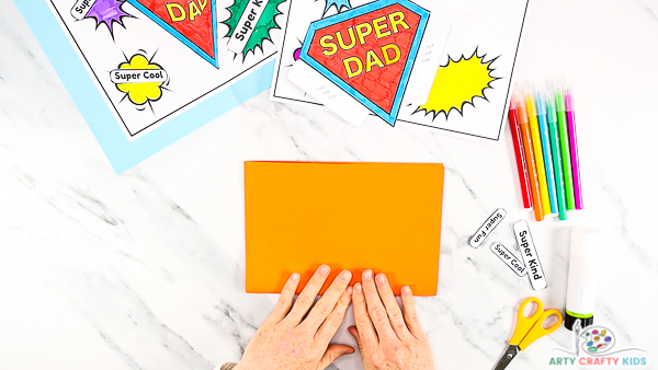 Image showing hands folding a sheet of orange card stock in half.